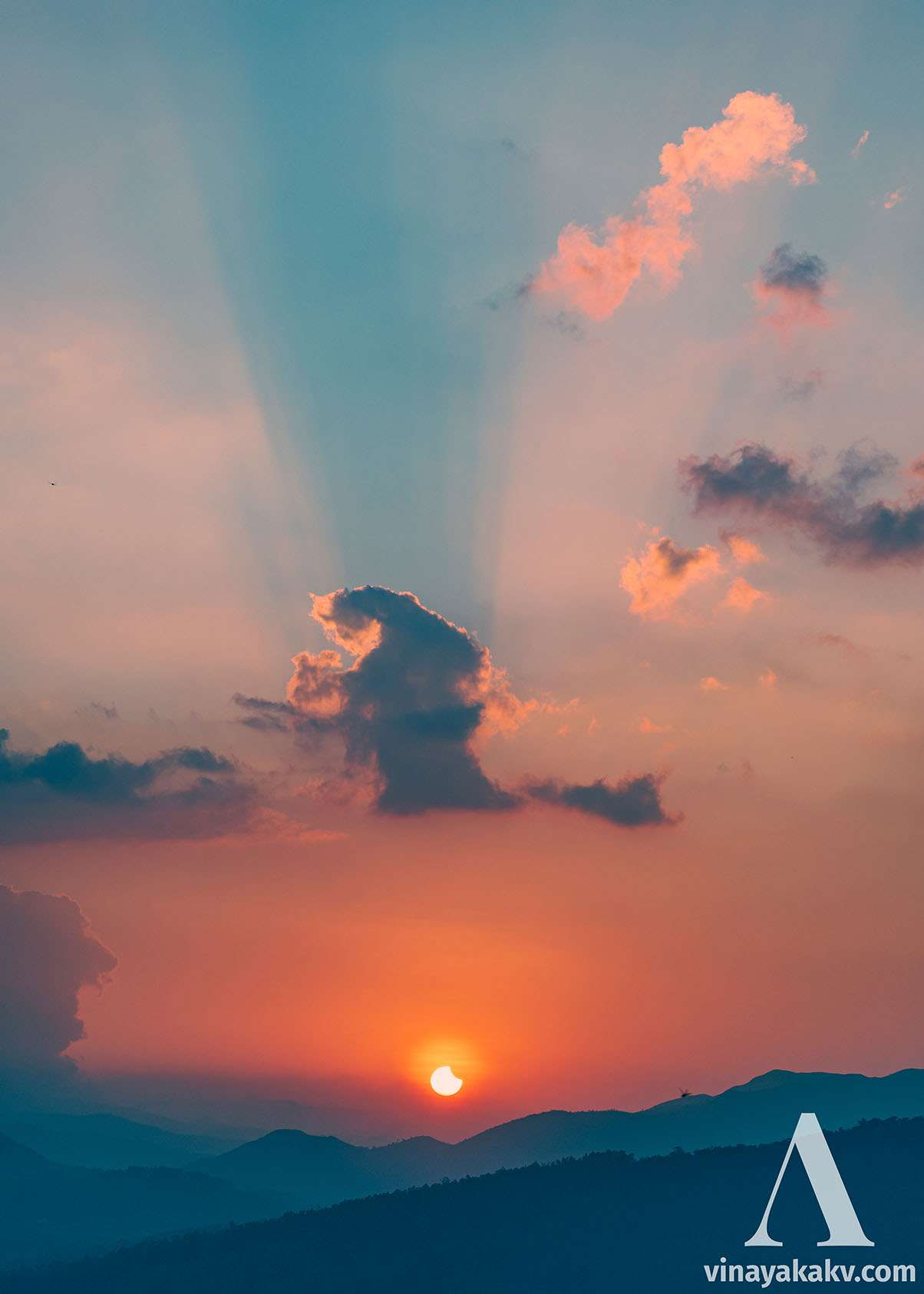 An eclipsed sun with the remains of the clouds that covered it before. A dragonfly is also in the frame